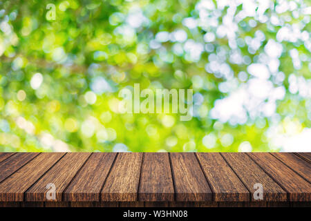 Leere Holztisch und abstrakte verschwommenes Grün bokeh Blätter Hintergrund Textur, Display Montage mit kopieren. Stockfoto