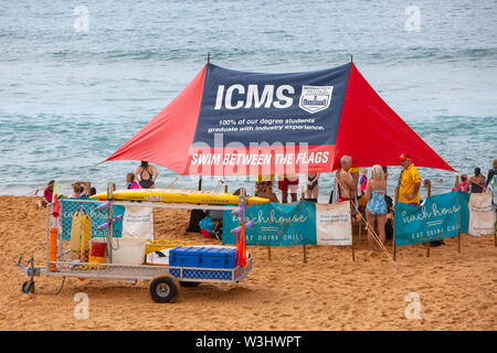 Freiwillige surf Rescue Team auf Sydney Avalon Beach mit Sonnenschirm Förderung schwimmen zwischen den Fahnen, Sydney, Australien Stockfoto