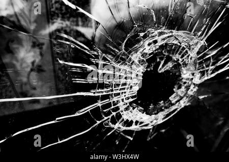 Viele Risse und ein Loch in die Fensterscheibe stilisierten Schwarzweiß-Film und Lomography Stockfoto