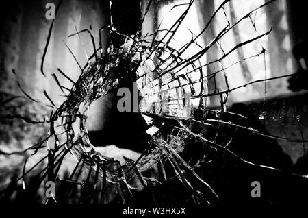 Viele Risse und ein Loch in die Fensterscheibe stilisierten Schwarzweiß-Film und Lomography Stockfoto