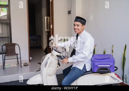 Asiatische muslimischer männlicher Reisen für Eid Mubarak lebaran durch die motorradhalterung. mudik Balik kampung Konzept per Motorrad Stockfoto