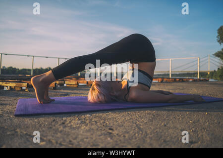 Frau Yoga üben an einem sonnigen Tag. Halasana/Pflug darstellen Stockfoto