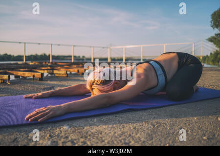 Frau Yoga üben an einem sonnigen Tag. Balasana, Kind darstellen. Stockfoto