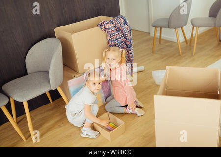 Zwei Mädchen. Süße hübsche Schwestern betrachten Sie beim Zeichnen auf der Box Stockfoto