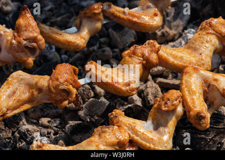 Lecker lecker Hähnchen Grill kochen auf Metall Spieße auf im Freien Holzkohlegrill mit duftenden Rauch. Nahaufnahme, selektiver Fokus auf Stücke von Stockfoto