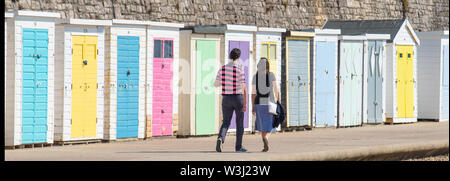 Lyme Regis, Dorset, Großbritannien. Juli 2019. UK Wetter: Herrliche heiße Sonne und blauer Himmel am Badeort Lyme Regis. Die Leute machen einen Spaziergang entlang der Strandhütten auf der Marine Parade. Die mediterrane Hitzewelle soll bis Freitag andauern. Quelle: DWR/Alamy Live News Stockfoto