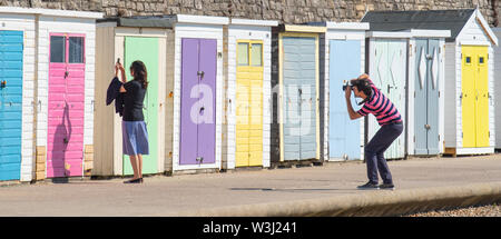 Lyme Regis, Dorset, Großbritannien. Juli 2019. UK Wetter: Herrliche heiße Sonne und blauer Himmel am Badeort Lyme Regis. Die Leute machen einen Spaziergang entlang der Strandhütten auf der Marine Parade. Die mediterrane Hitzewelle soll bis Freitag andauern. Quelle: DWR/Alamy Live News Stockfoto