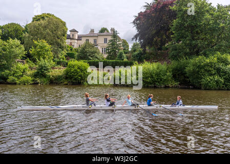 Lady rowers am Fluss Dee Chester vorbei an einem der schönen Häuser in Queens Park. Stockfoto