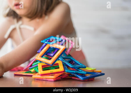 Porträt der schönen kleinen Mädchen spielen bunt magnet Kunststoff Bausteine Kit, Tagträumen und Bild Ideen in Ihrem Verstand. Kreative Stockfoto