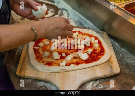 Hinzufügen von Mozzarella zu einer Pizza Stockfoto