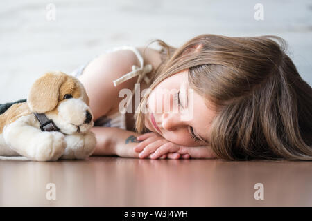 Portrait von schönen Mädchen schlafen mit Ihrem Liebling Plüsch Stofftier hund Puppe Spielzeug. Stockfoto