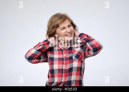 Reife Frau mit Schmerzen in ihrem Nacken. Stockfoto