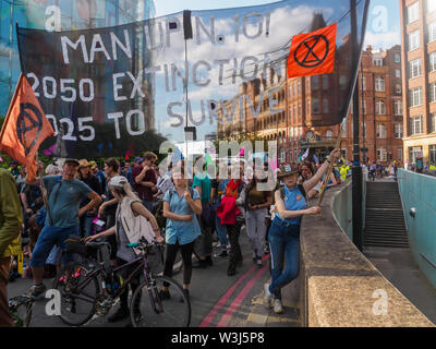 London, Großbritannien. 15. Juli 2019. Ein großes Banner fordert Nr. 10 auf 'Meine' und das Aussterben auf dem Aussterben Rebellion März aus der Royal Courts of Justice zu Ihrem Aufstellungsort Gesicht für die nächsten drei Tage bei Waterloo Millennium Grün. Sowie die Demonstranten mit Transparenten, es gab ein riesiges rosa Dodo, und an der Rückseite der Prozession der Yacht Polly Higgins, für die Umwelt Rechtsanwalt, der seit Jahren für ein Gesetz gegen Umweltzerstörung kämpfte und starb im April dieses Jahres benannt. Credit: Peter Marschall/Alamy leben Nachrichten Stockfoto