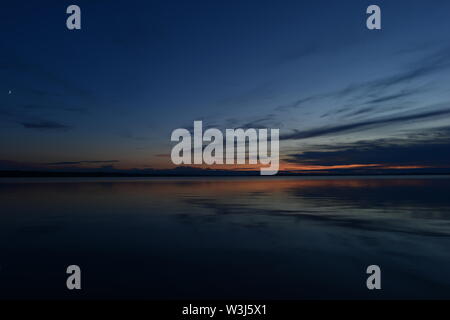 Blauer Himmel in das Licht und die Schatten der Dämmerung am Aufgang der Mond in der Stille der Wasser des Sees Stockfoto