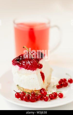 Stück von Souffle Kuchen mit Zweige rote Johannisbeere auf dem Hintergrund der hinter Saft in einer Schale Stockfoto