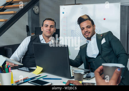 Zwei junge Unternehmer unterschiedlicher Nationalität in Anzügen im Büro Stockfoto