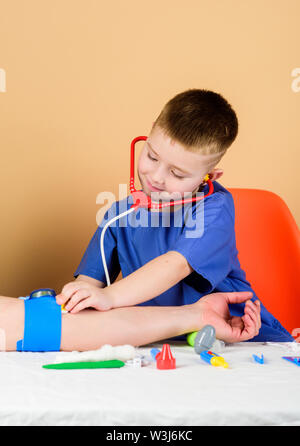 Kid messen Druck zu Patienten. Hausarzt. Die bestrahlungsverordnung. Kinderarzt intern. kleiner Junge in der medizinischen Uniform. Krankenhaus. Medizin und Gesundheit Kind Arzt Patienten mit Stethoskop. Stockfoto