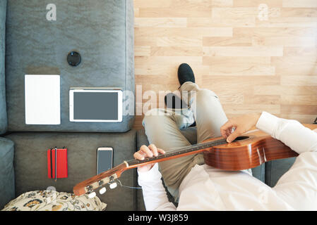 Kaukasische Mann spielt eine Spanische Gitarre im Wohnzimmer. Overhead shot von oben und leere Raum für Editor's Text. Stockfoto