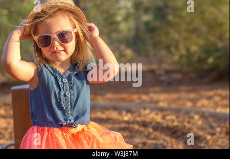 Eine hübsche blonde Mädchen im Park. Sie trägt einen Hut und Sonnenbrille Stockfoto