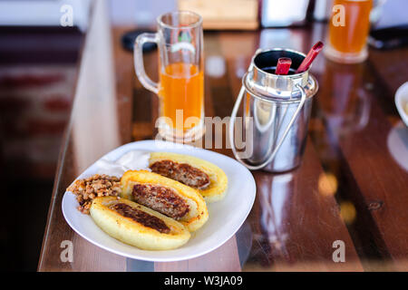 Gebratene cepelinai, Knödel aus gerieben und riced Kartoffeln und gefüllt mit Hackfleisch mit saurer Sahne. Nationalgericht Litauen close-up an der Platte. Stockfoto