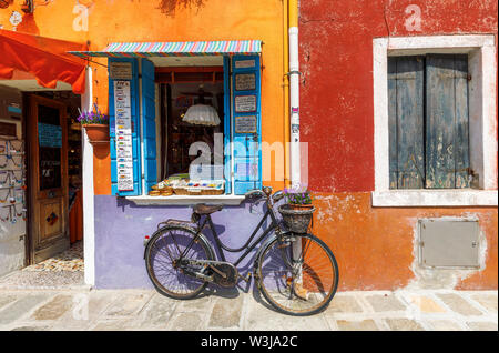 Rusty's vintage Frau Fahrrad außerhalb ein helles Orange geparkt und lila lackiert Souvenir shop in Burano, einer kleinen Insel in der Lagune von Venedig, Venedig, Italien Stockfoto