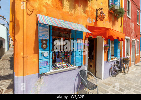 Rusty's vintage Frau Fahrrad außerhalb ein helles Orange geparkt und lila lackiert Souvenir shop in Burano, einer kleinen Insel in der Lagune von Venedig, Venedig, Italien Stockfoto