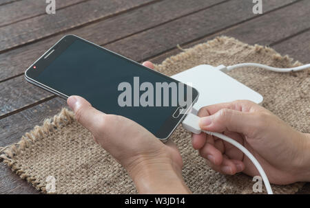 Frau verbunden sind Ladekabel mit dem Smartphone durch externe Batterie. Stockfoto