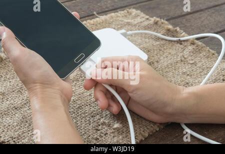 Frau verbunden sind Ladekabel mit dem Smartphone durch externe Batterie. Stockfoto