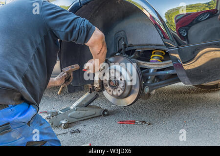 Ein Mann änderungen Bremsbeläge auf ein Auto. Stockfoto