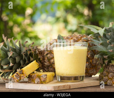 Ananassaft und Ananasscheibe auf einen hölzernen Tisch gelegt. Stockfoto