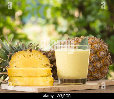 Ananassaft und Ananasscheibe auf einen hölzernen Tisch gelegt. Stockfoto