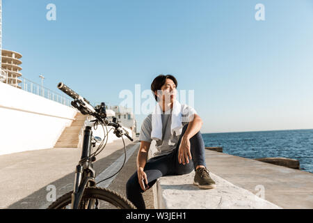 Junge passen asiatischer Mann Radfahrer, Külschrank, sitzen am Meer Stockfoto
