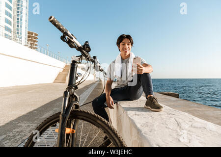 Junge passen asiatischer Mann Radfahrer, Külschrank, sitzen am Meer Stockfoto