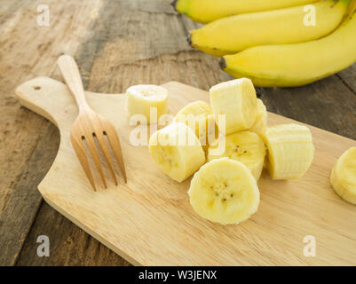 In Scheiben geschnittene reife Banane Stücke auf einem Holztisch. Stockfoto