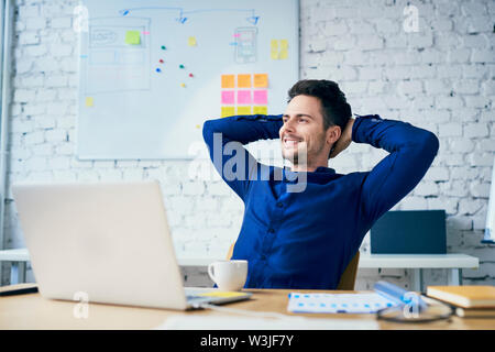 Zufrieden junger Mann im Büro weg schauen Stockfoto