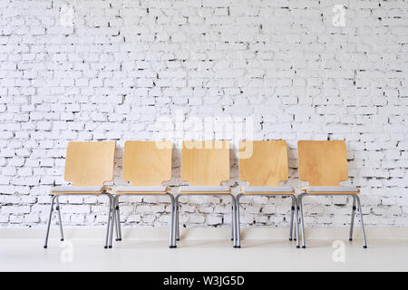 Reihe von fünf Leer moderne Stühle vor der stilvollen brick wall Stockfoto