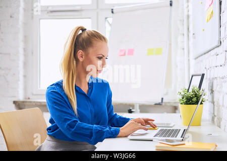 Schönen selbstbewussten jungen Frau, die Arbeiten am Laptop in alternative moderne Büro Stockfoto