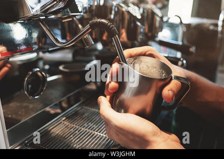 Barista Mann dampfende Milch in schäumenden Krug mit professioneller Kaffeemaschine cappuccinator im Cafe Stockfoto