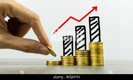 Langfristige Investitionen oder Geld verdienen mit der richtigen Konzepte. Ein Geschäftsmann, Münze auf Stapel von Münzen auf eine Tabelle mit wachsenden Graph auf Münzen pil Stockfoto