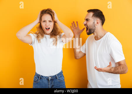 Bild von streiten Paare der Mann und die Frau in der Basic T-shirts an einander beim Kampf um einen gelben Hintergrund schreien Stockfoto