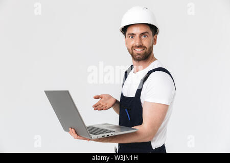 Sicher glücklich Bärtigen builder Mann, Overalls und hardhat auf weißem Hintergrund, mit Laptop Stockfoto