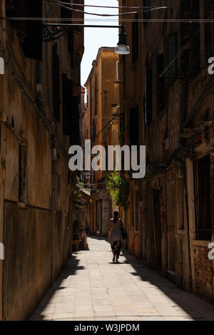 Frauen, die mittags eine enge Straße entlang laufen, Venedig, Italien Stockfoto