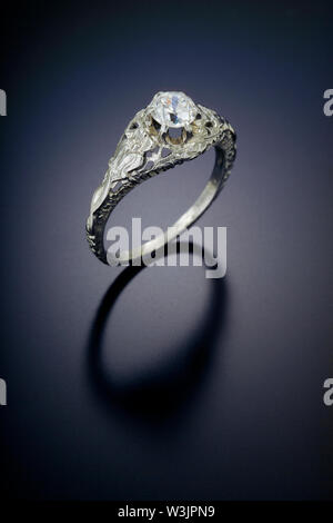 Einen filigranen Stil antike Diamond Engagement Ring mit einem in Platin plus carat Zentrum Stein gesetzt. Auf einem schwarzen reflektierenden Hintergrund dargestellt. Stockfoto