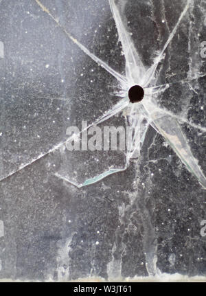Ein einschußloch in einem Fenster der alten, dreckigen Glas in einer verlassenen und verfallenen Lager Stockfoto