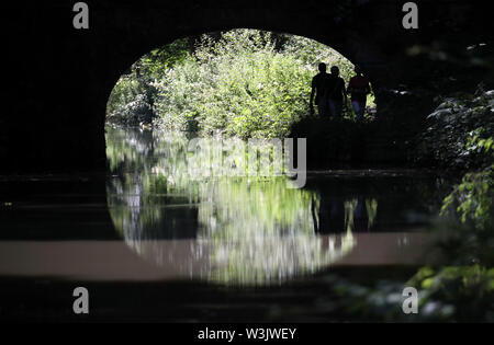 Silhouette Menschen sind, wie Sie unter einer Brücke auf der Basingstoke Canal in der Nähe von Frogmore, Hampshire, wie mehr heiße Wetter zurückzuführen ist Großbritannien in dieser Woche zu schlagen. Stockfoto