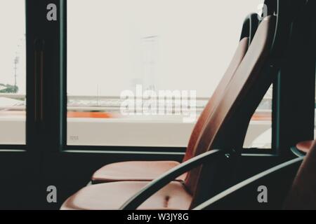 Leere Passagiersitze in einem Bus mit verschwommenem Hintergrund Aus dem Fenster Stockfoto