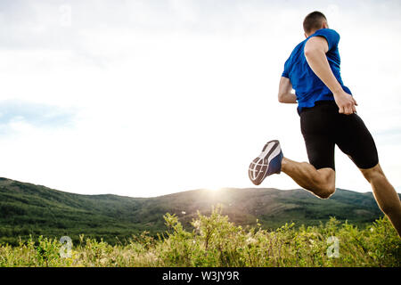 Athlet runner Dynamische auf Sommer Hochplateau motley Gras im Sonnenuntergang Stockfoto