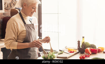 Reife Frau bereitet frische organische Salat in der Küche Stockfoto