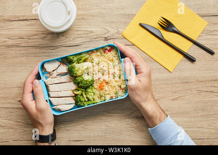 7/8-Ansicht der Mann am Tisch sitzen und halten Lunch Box mit Gesundes und schmackhaftes Essen Stockfoto