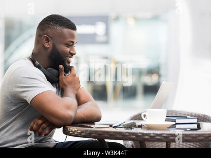 Fröhlich afrikanische amerikanische Mann gerade am Laptop Bildschirm Stockfoto